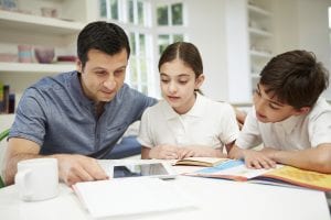 father helping son and daughter with homework